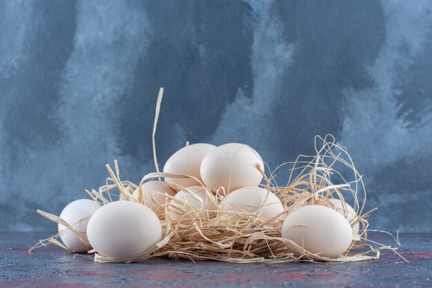 Uova di gallina bianche e marroni fresche con fieno.