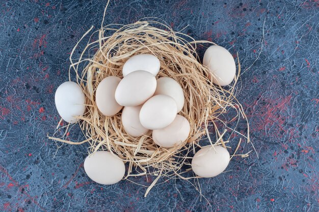 Uova di gallina bianche e marroni fresche con fieno.