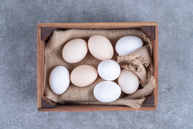 Uova di gallina bianche fresche su un canestro di legno