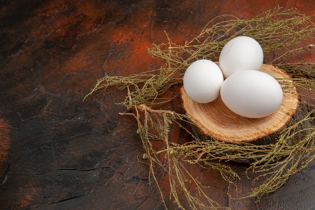 Uova di gallina bianche vista frontale sulla superficie scura