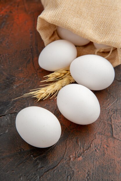 Uova di gallina bianche vista frontale sulla superficie scura