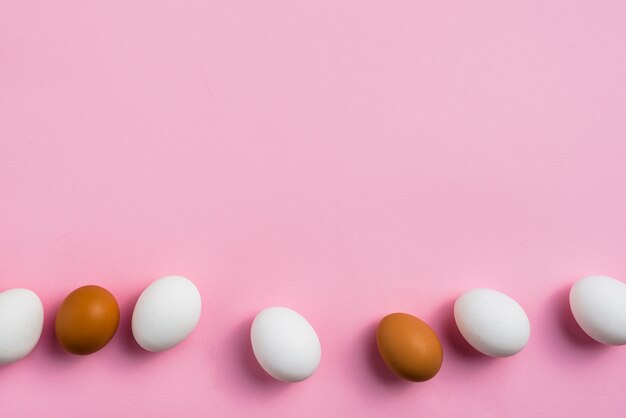 Uova di gallina sparse sul tavolo rosa