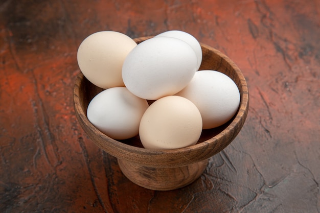 Uova di gallina vista frontale all'interno del piatto su superficie scura