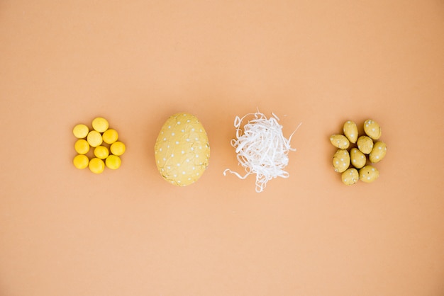 Uova di Pasqua al cioccolato con piccole caramelle sul tavolo beige