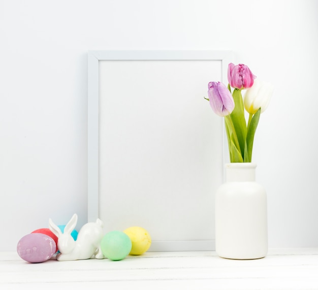 Uova di Pasqua con i tulipani in vaso e cornice vuota