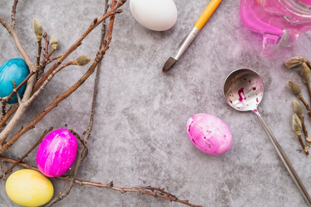 Uova di Pasqua vicino a cucchiaio, ramoscelli di salice e pennello