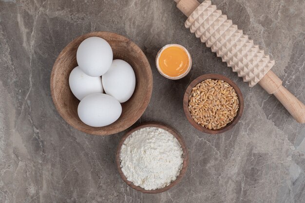 Uova, farina, orzo e mattarello sulla superficie di marmo. Foto di alta qualità