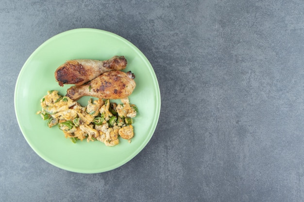 Uova fritte e cosce di pollo sul piatto verde.