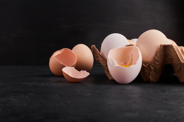 Uova intere e gusci d'uovo in vassoio di cartone.