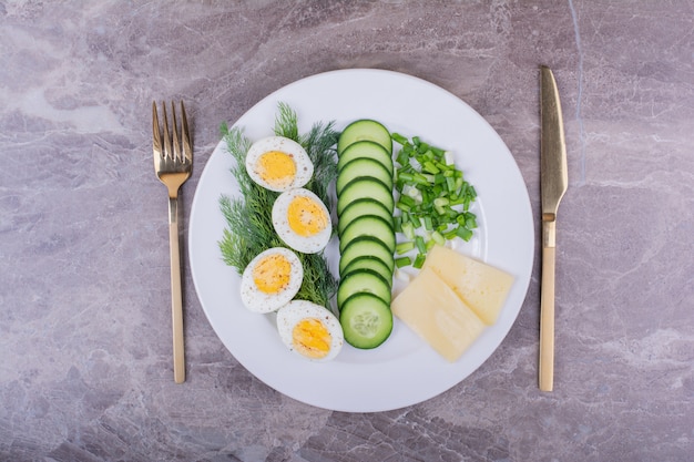 Uova sode con insalata verde in un piatto bianco.