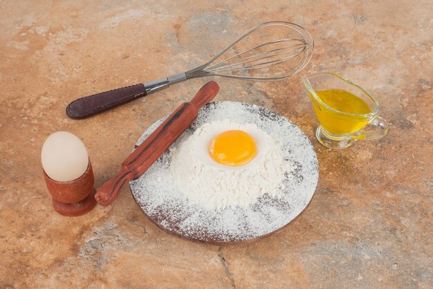 Uovo crudo con wgisk e tavola di legno.
