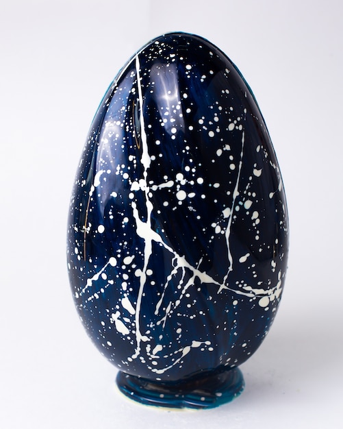 Uovo di cioccolato blu di vista frontale in bianco macchiato sul supporto