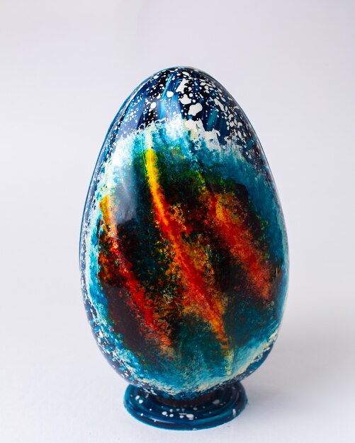 Uovo di cioccolato colorato vista frontale sul supporto
