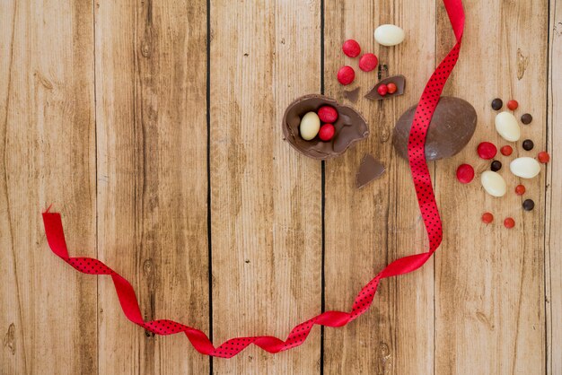 Uovo di cioccolato vicino caramelle e nastro