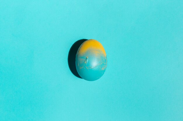 Uovo di Pasqua colorato sul tavolo blu