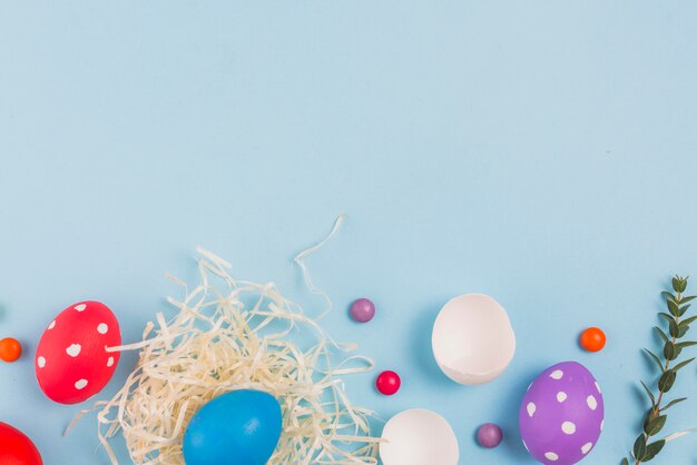 Uovo di Pasqua nel nido con ramo di pianta verde e caramelle