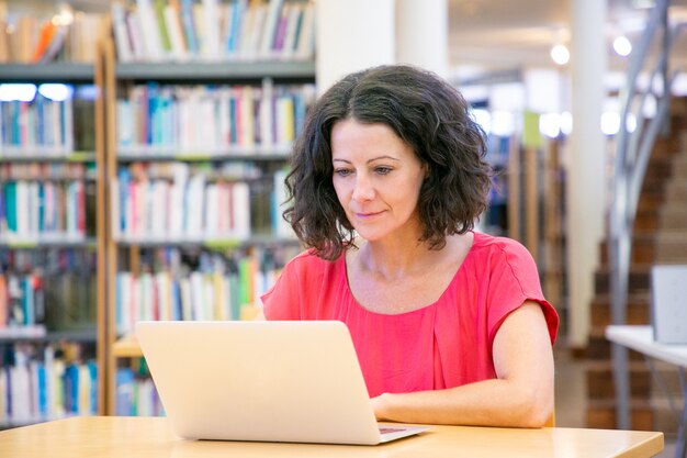 Utente femminile emozionante serio che lavora al computer