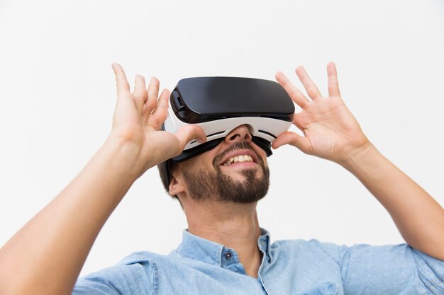 Utente maschio sorridente che indossa i vetri di VR, dispositivo di regolazione