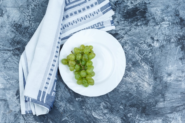 Uva bianca piatta laici nel piatto bianco con asciugatutto su sfondo di marmo blu scuro. orizzontale