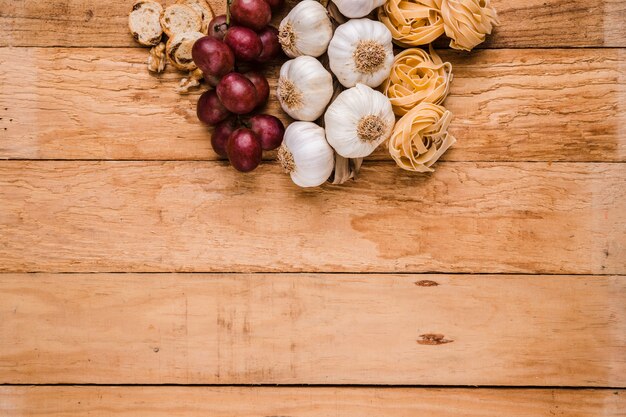 Uva biologica; mazzo di bulbi di aglio con pasta cruda e pane su carta da parati texture