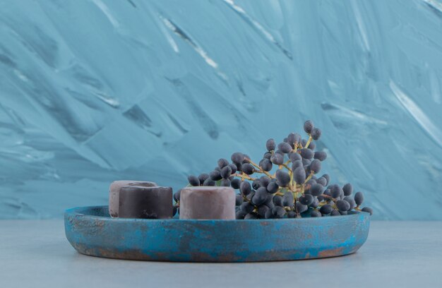 Uva e dolce sul vassoio, sullo sfondo di marmo. Foto di alta qualità