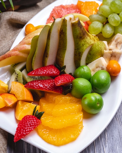 Uva e prugna di ciliegia della pera del kiwi della banana della fragola dell'arancia del piatto di frutta di vista laterale