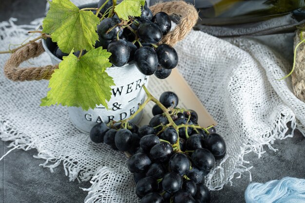 Uva fresca con foglie nel secchio su tela di sacco