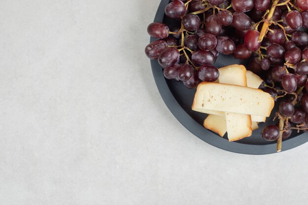 Uva rossa fresca e fette di formaggio su tavola scura