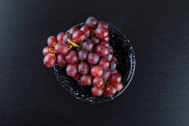 Uva rossa in una ciotola su grigio scuro,