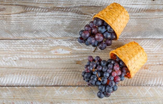 Uva rosso scuro in cesti di vimini su sfondo di legno, piatto laici.