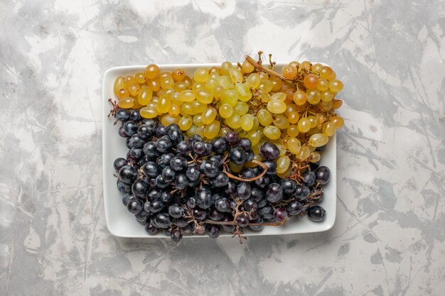 Uva succosa fresca di vista superiore all'interno della zolla sulla frutta fresca del vino di superficie bianca pastosa