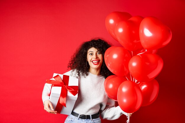 Vacanze e celebrazione buon compleanno ragazza con regalo e in posa vicino a palloncini di elio festa sorrisi...