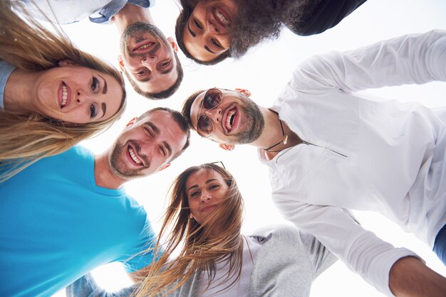 Vacanze estive, persone felici - un gruppo di adolescenti che guardano in basso con un sorriso felice sul volto.