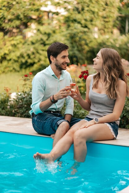 Vacanze estive, persone, romanticismo, concetto di incontri, coppia che beve spumante mentre si gode del tempo insieme seduti a bordo piscina