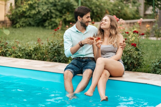 Vacanze estive, persone, romanticismo, concetto di incontri, coppia che beve spumante mentre si gode del tempo insieme seduti a bordo piscina