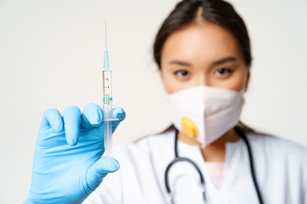 Vaccinazione covid e concetto di quarantena medico donna asiatica nel respiratore facciale che mostra la siring...