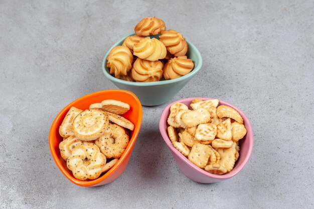 Vari biscotti e biscotti in ciotole colorate sulla superficie di marmo.