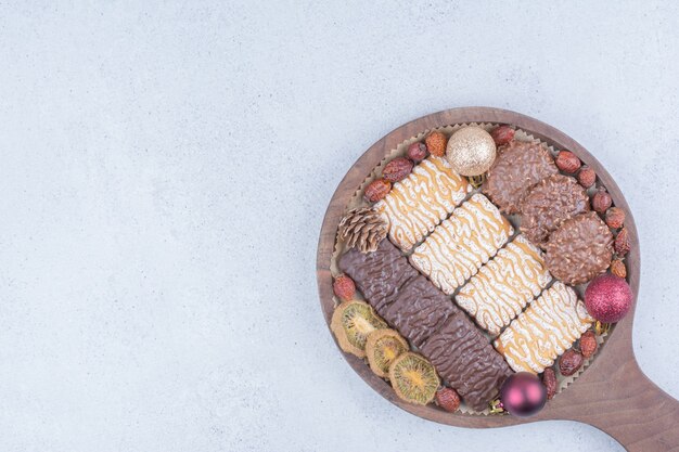 Vari biscotti, frutta secca e palline di Natale su tavola di legno.