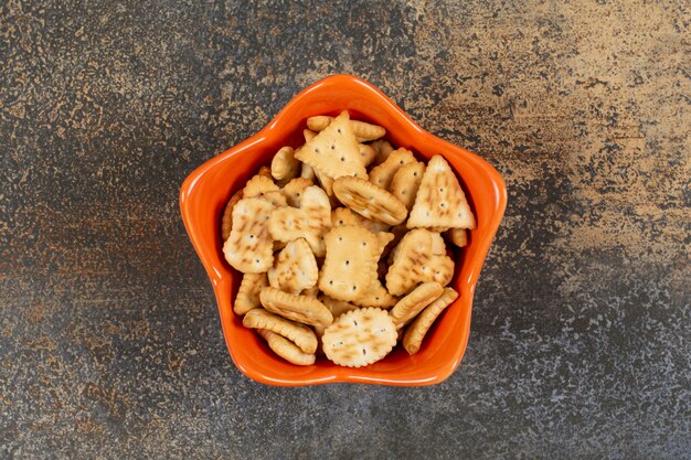 Vari cracker salati a forma di in ciotola arancione.