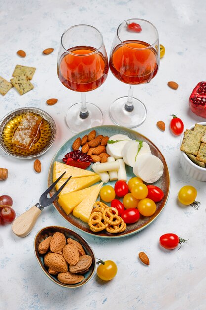 Vari formaggi e piatto di formaggi sul tavolo luminoso con diversi tipi di noci e frutta