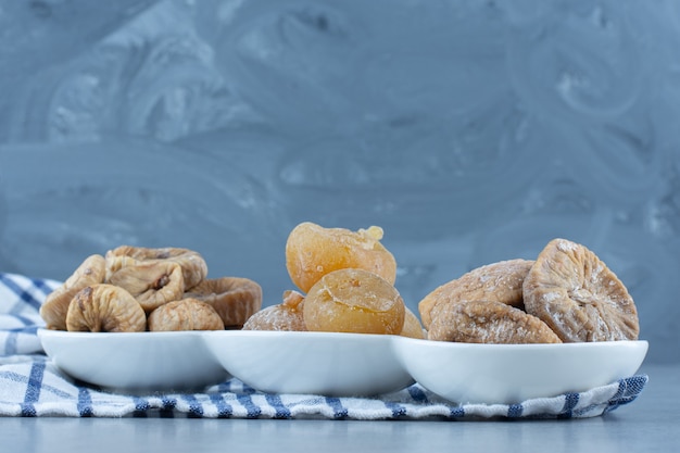 Vari frutti secchi nella ciotola, sullo strofinaccio, sul tavolo di marmo.