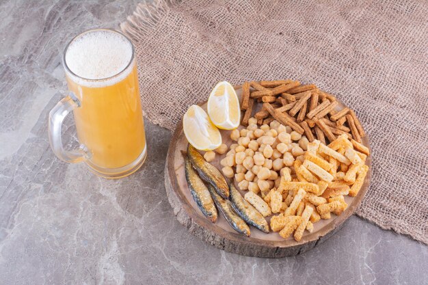 Vari snack sul pezzo di legno con un bicchiere di birra. Foto di alta qualità