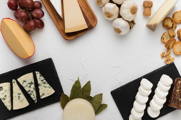 Vari tipi di formaggi con uva gustosa e ingrediente su sfondo bianco