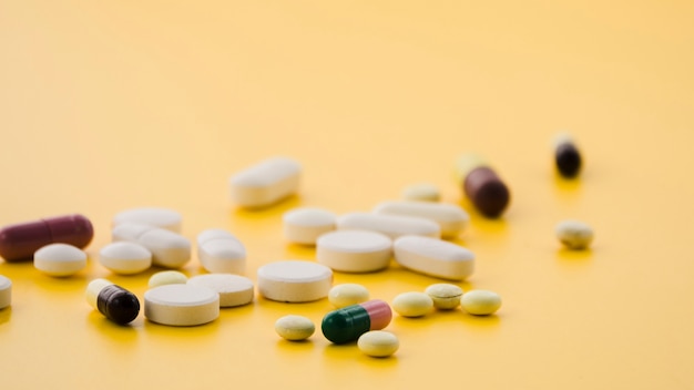 Vari tipi di pillole colorate su sfondo giallo