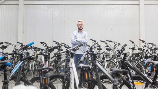 Varie biciclette che circondano meccanico maschio che sta nell&#39;officina