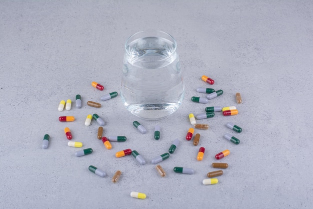 Varie capsule farmaceutiche e bicchiere d'acqua. Foto di alta qualità