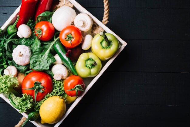 Varie verdure fresche in contenitore sulla superficie in legno nero