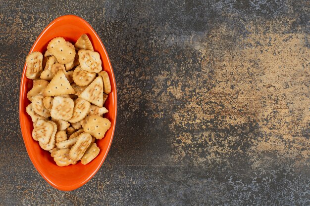 Varietà di cracker salati in ciotola arancione.