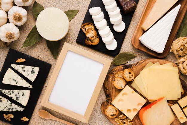 Varietà di formaggi e ingredienti sani con cornice bianca vuota su sfondo texture