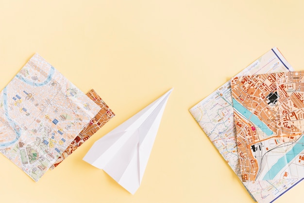 Varietà di mappe con aeroplano di carta bianca su fondo beige